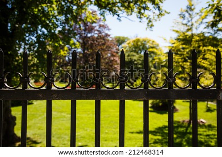 An old black, wrought iron fence around a formal garden