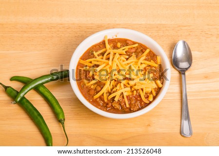 A bowl of chili con carne with beans and green chili peppers