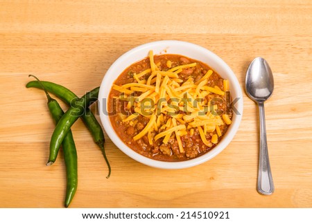 A bowl of chili con carne with beans and green chili peppers