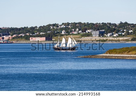 Large Black Schooner with White sails on blue water
