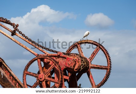 An old rusty, red crane on the island of St Croix with a white crane or egret on top