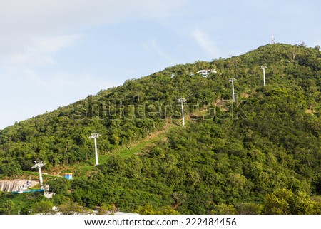 Towers and cables for cable car ride up a green tropical hill