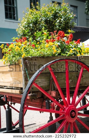 An old wood cart with large red wagon wheel used as a garden planter