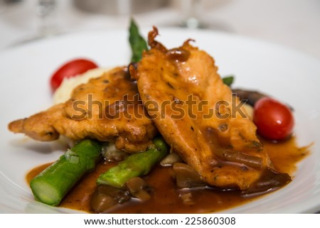 Dinner of chicken marsala with mushroom sauce over fresh asparagus