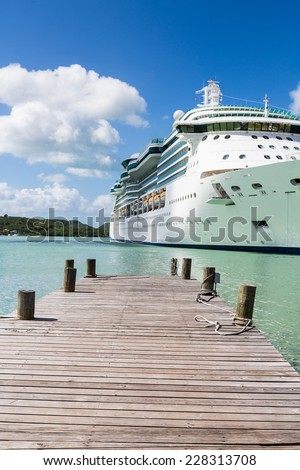 Rope coiled on an old wooden pier with a white luxury cruise ship in the background