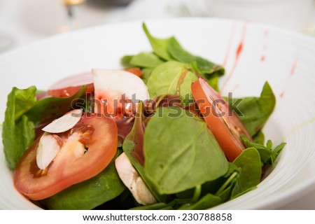 A fresh spinach salad with sliced tomatoes and mushrooms and a raspberry vinaigrette
