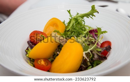 A fresh salad of field greens, red cherry tomatoes and cut yellow tomatoes