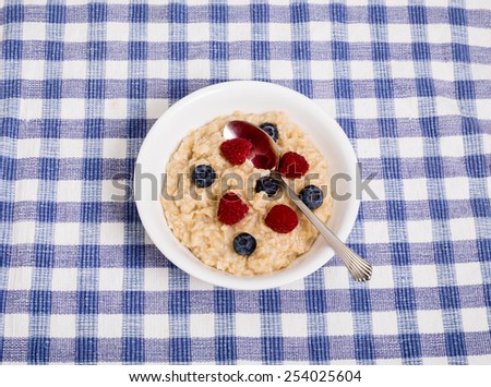 Bowl of hot, fresh oatmeal with raspberries and blueberries