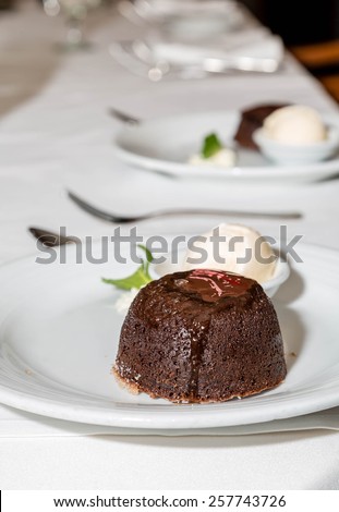 A delicious dessert of chocolate lava cake with a scoop of vanilla ice cream on a formal dinner table