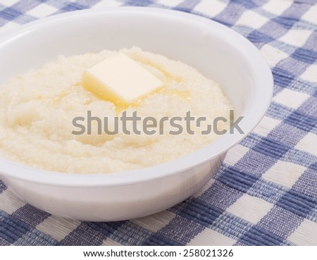 A bowl of white corn grits on a blue plaid placemat