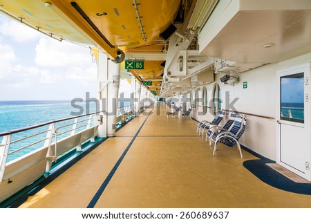 Deck of a luxury cruise ship with chairs and lifeboats