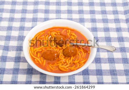 A bowl of canned spaghetti with meatballs and a spoon