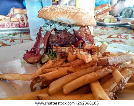 Fresh cooked french fries with a massive bacon, blue cheese burger at a restaurant