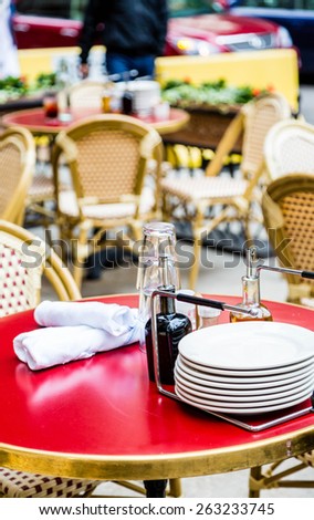 Stack of plates on red outdoor table with linen napkins