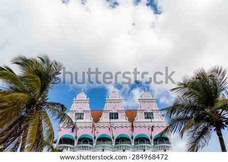 Colorful building in Aruba with pink stucco, flags and green awnings