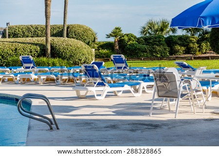 Blue patio furniture on deck between swimming and ocean