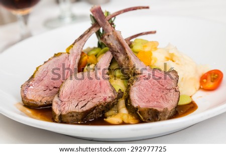 Three medium rare lamb chops on a bed of vegetables