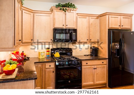 A bright and modern kitchen with wood cabinets and black appliances