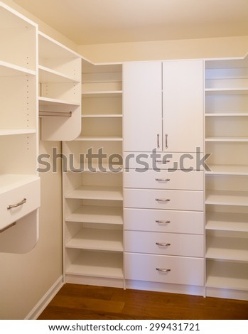 Custom white wood cabinetry in a walk in closet