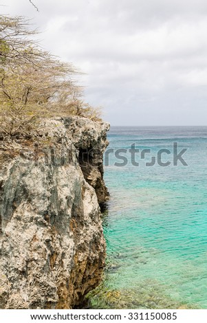 A rocky cliff overlooking aqua water on Curacao