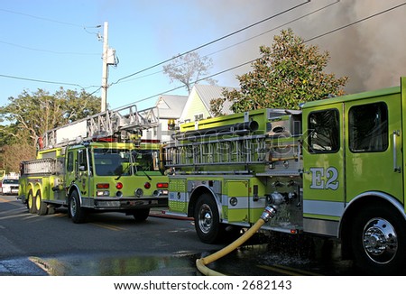 Yellow fire trucks at the scene of a house fire