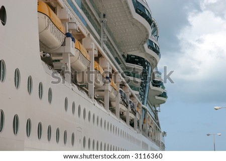 Side of a cruise ship showing portholes and lifeboats