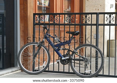 A black bike leaning against a black iron fence
