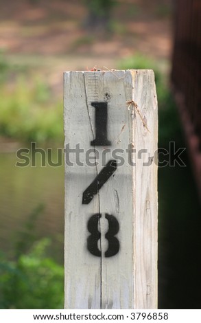 A wooden mile marker on a woodland trail