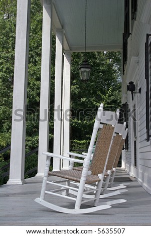 Old white rocking chairs on a colonial porch with white columns