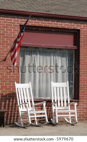White rocking chairs on the sidewalk of a public street