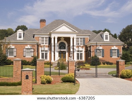 A massive brick house behind a brick and iron fence