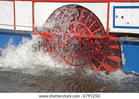 A red paddle wheel on a boat churning through the water