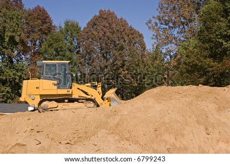 Heavy construction equipment on top of a large pile of dirt
