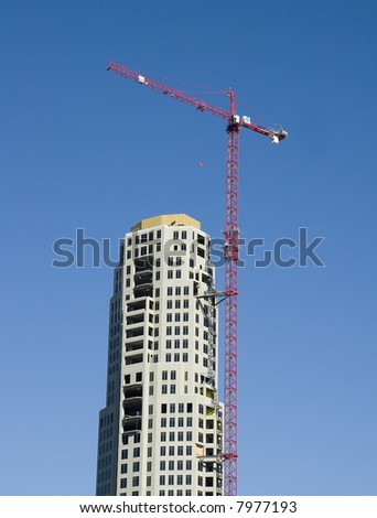 A high rise construction project with a red crane on top