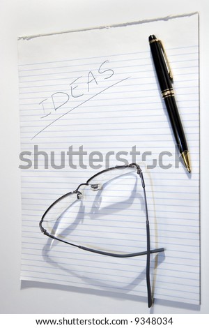 A pad of paper for Ideas with a pen and glasses