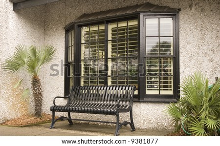 A black iron bench in front of a window to a store or restaurant