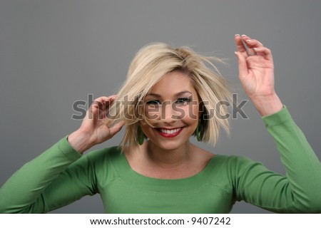 A blonde fashion model in green blouse messing up her hair