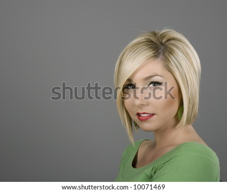 A blonde in a green blouse with a slight smile