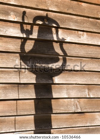 An old barn with the shadow of a dinner bell on the wood