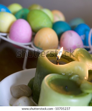 Green candles burning in front of many colored easter eggs