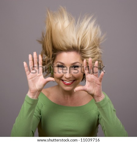 A blonde in a green blouse and her hands out with her hand standing up