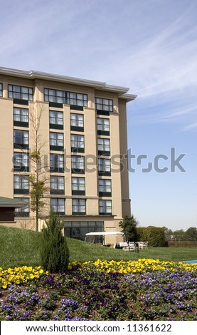 A nice hotel with landscaped flower beds against a blue sky and clouds