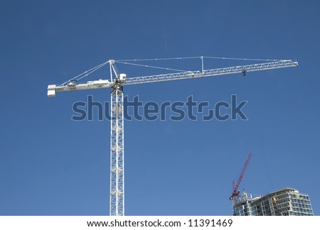 A white construction crane over a job site against a blue sky