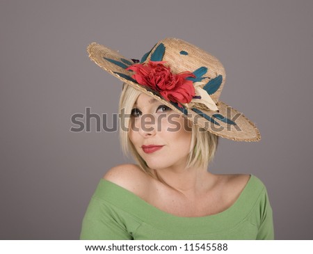 A blonde in a green blouse and a flowered hat slanted to one side