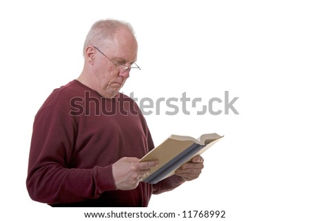 An older guy wearing reading glasses standing and looking at a book