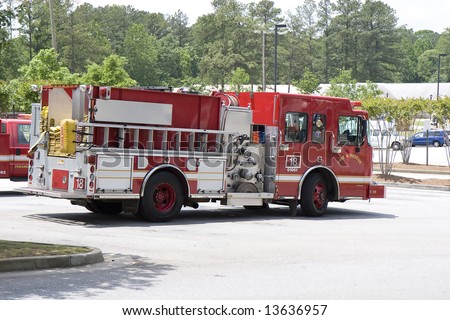 A bright red fire truck on duty in a parking lot