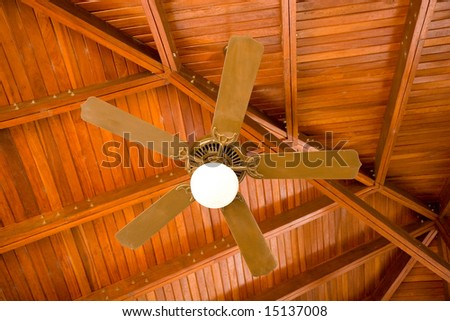 A ceiling fan and light fixture under a wood pavilion roof