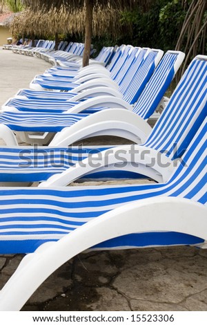Blue and White striped lounge chairs along a tropical pool