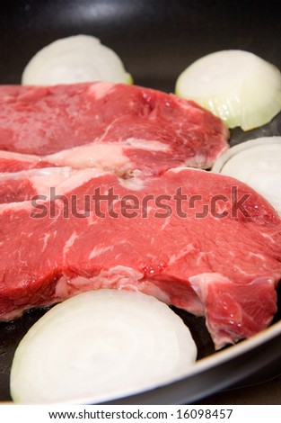 Strip steaks and sliced onions in a pan ready for cooking