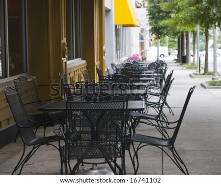 Rows of iron tables on a sidewalk outside a restaurant